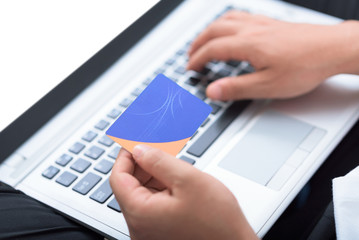 Man's hands holding credit card and using laptop for online payment.