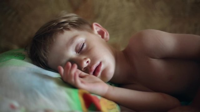 Little boy sleeping, in the dream his face muscles and body twitches, he dreams, he wakes up and stretches