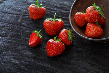 Red fresh strawberries on black rustic wood background