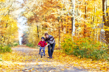 Obraz premium Little kid boy and father with bicycle in autumn forest