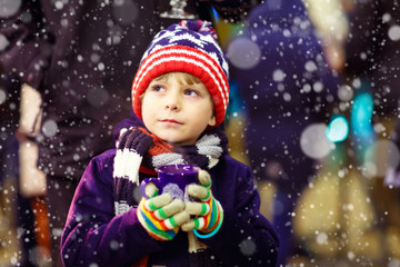 Obraz na płótnie Canvas Little kid boy with hot chocolate on Christmas market
