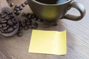 Coffee cup, coffee beans on wooden table with Blank note paper.