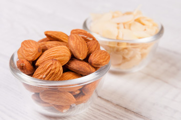 Almond nuts and sliced shavings in small glass dishes on wooden table