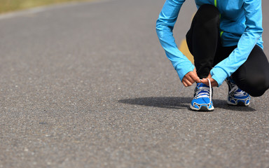  young  woman runner tying shoelace on road