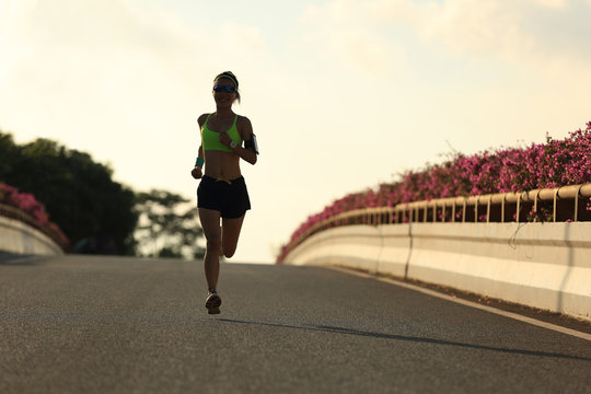 young woman runner running on city bridge road