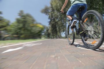 Boy riding bike on bicycle lane in park. Speed motion blur.