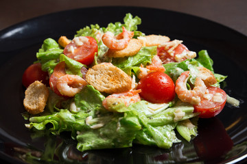 Caesar Salad with Shrimp on a black plate