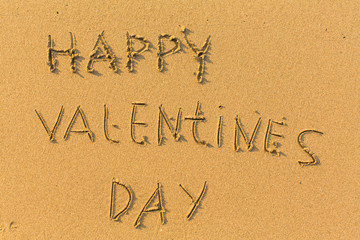 Happy Valentines Day - hand-drawn in gentle sea beach sand.