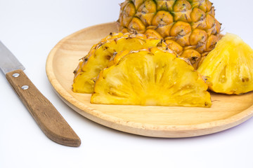 Pineapple fruit cut on wooden plate on white background