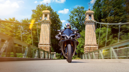 Motorrad fährt über Brücke mit sommerlicher Stimmung und Bewegungsunschärfe