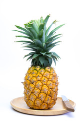 Pineappleand knife on wooden plate on white background