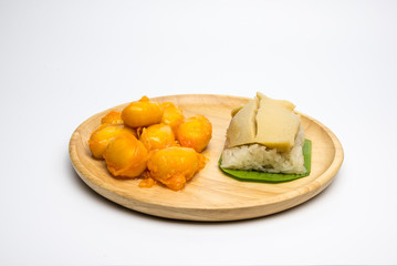 Thai Bean and Egg Yolk Dessert (Met Khanoon: THAI Dessert )and sticky rice and egg custard creamy wrapped banana leaf, on a wooden plate.