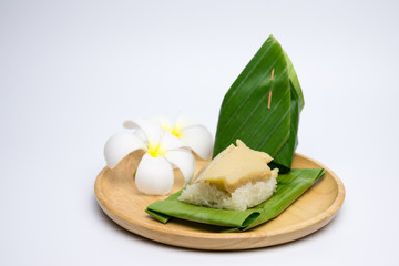 Thai Dessert, sticky rice and egg custard creamy wrapped banana leaf, on a wooden plate,