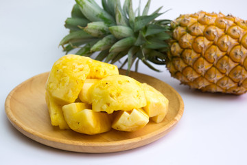 Pineapple fruit cut on wooden plate on white background