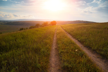 red sunset over green field with road