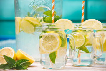 Lemonade drink in the jug on the white table near the pool