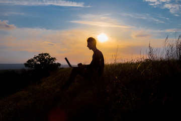 silhouette of happy business man with laptop working on the field