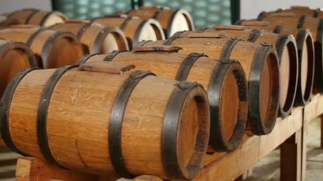 dolly shot of balsamic vinegar casks in row in old winery where wine ages to become vinegar  
