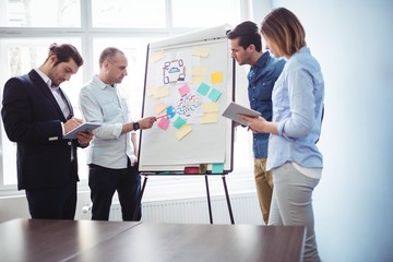 Colleagues discussing in meeting room using white board