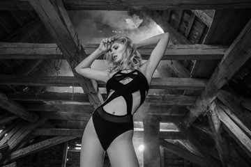 Bottom view of blonde sensual woman posing in old wooden attic of abandoned building with smoke...