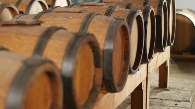 dolly shot of balsamic vinegar barrels in row in old winery where wine ages to become vinegar
