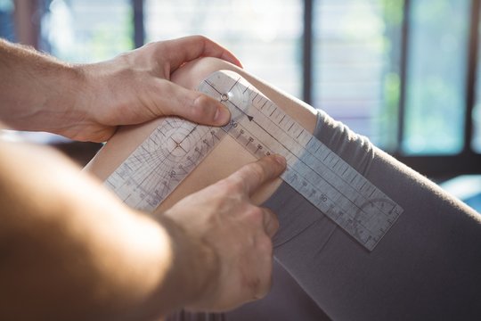 Male therapist measuring female patient knee with goniometer
