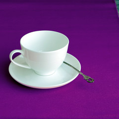White porcelain tea cup with tea spoon on a table. Toned image.