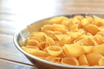 Dry conchiglie pasta shells in a stainless steel bowl