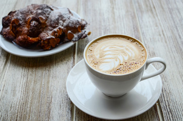 Delicious breakfast : cappuccino coffe cup served with almond croissant on grey background.