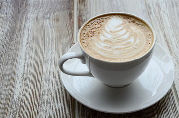 Latte art: Rosetta on a cappuccino coffe cup served on grey background. Copy space.