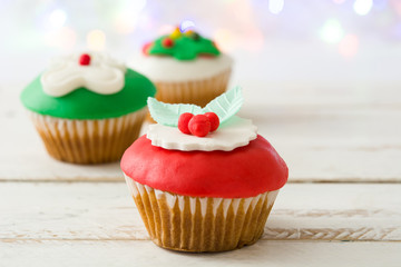 Christmas cupcakes and lights on white wooden table

