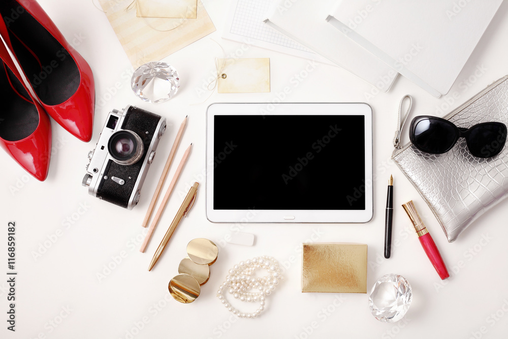 Wall mural Workplace with tablet, photo camera, pen, high heels, lipstick and sunglasses. Flat lay composition. Top view