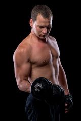 Fototapeta na wymiar portrait of an athlete with dumbbells while training in a dark r