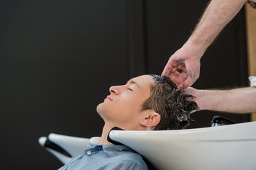 Young man at hairdresser salon getting his hair washed