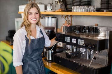 Portrait of smiling waitress making cup of coffee