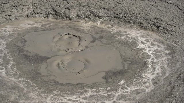 A natural phenomenon called a mud volcano. Small geysers of mud erupt from the ground to form little volcano.