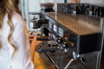 Mid section of waitress making cup of coffee