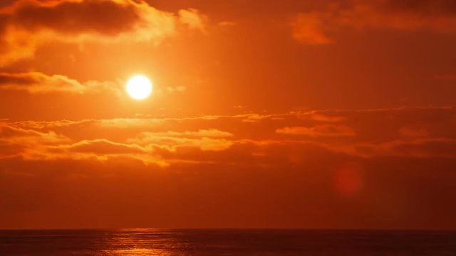 Time Lapse of the Sun through the clouds with the ocean in the forground.