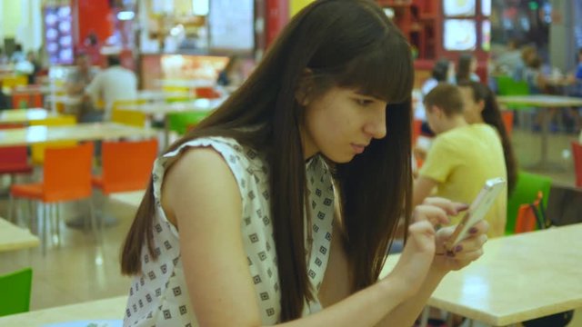 Young woman playing indoor at cafe, using smart phone. Girl play the popular smartphone game