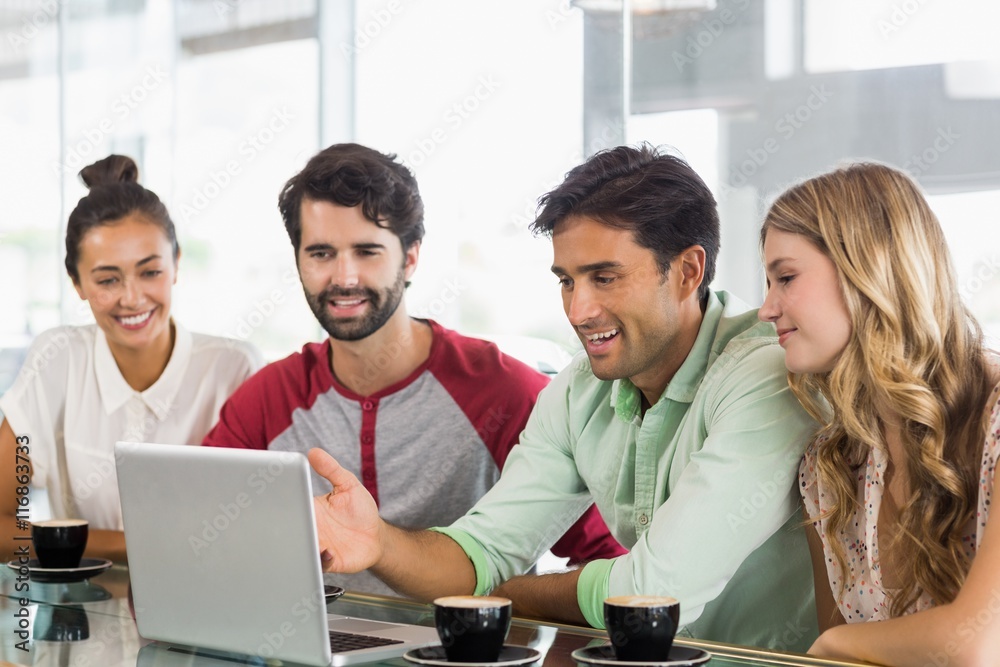 Poster group of friends using laptop while having cup of coffee