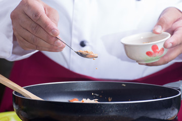 Chef putting crushed peanut to pan