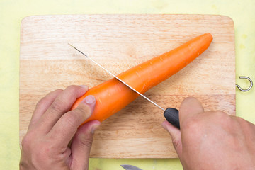 Chef cutting carrot on a wooden board