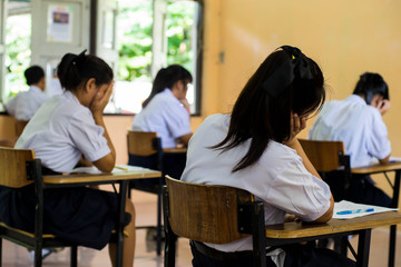 Thai Students sitting in an exam hall doing an exam in hight sch