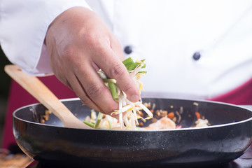 Chef putting bean sprouts and leek to the pan