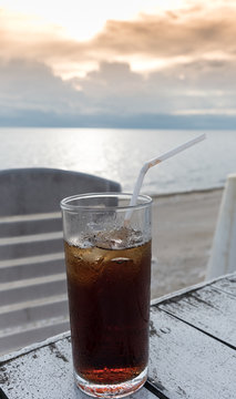 A glass of cola for refresh with sunset on the beach