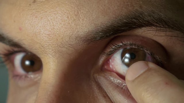 Young man put in contact lenses
