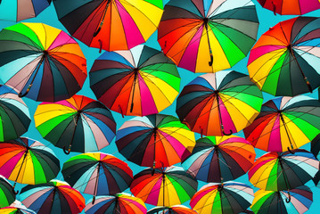 Fototapeta na wymiar Colorful umbrella with colors of rainbow in the blue clear sky. Conceptual bright background.