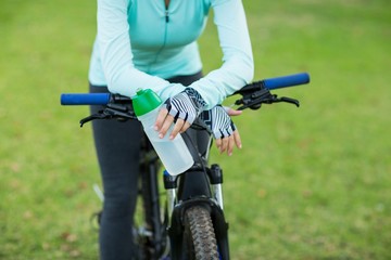Mid section of cyclist holding water bottle