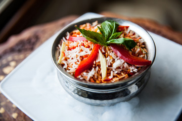 Biryani in metal pot on the table in cafe
