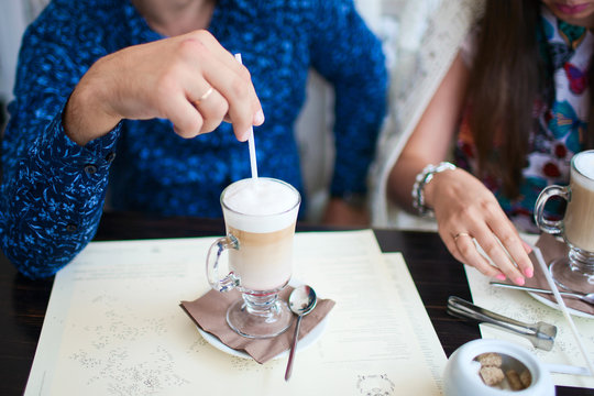 Loving couple sitting in a cafe. Closeup of a male hand with coffee